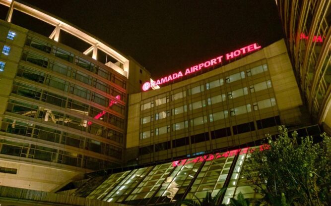 A view of the Ramada Pudong Airport Hotel lit up at night with a big red sign on the roof