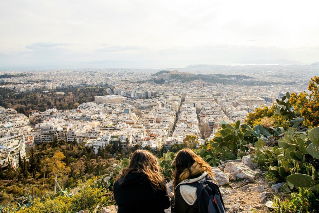 View of the Acropolis and Athens cityscape from Lycabettus Hill, with two women admiring the panorama