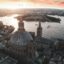 A panoramic view of Valletta, Malta at sunset, with historic domes, church spires, and the harbor in the foreground. Travelers booking a Malta airport transfer can enjoy this scenic arrival to the city, with boats on the water and a warm evening sky overhead.