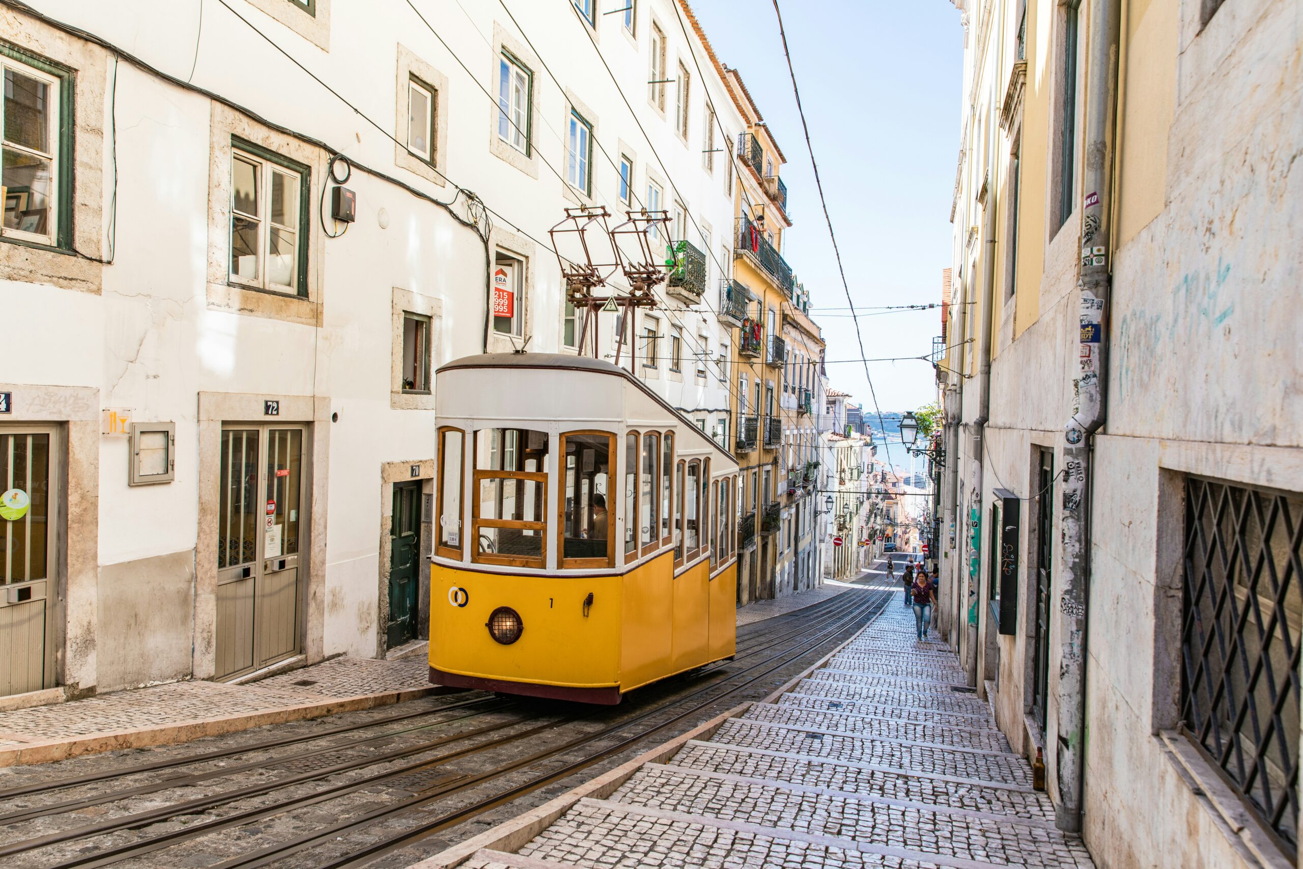 yellow trolley going up a city street