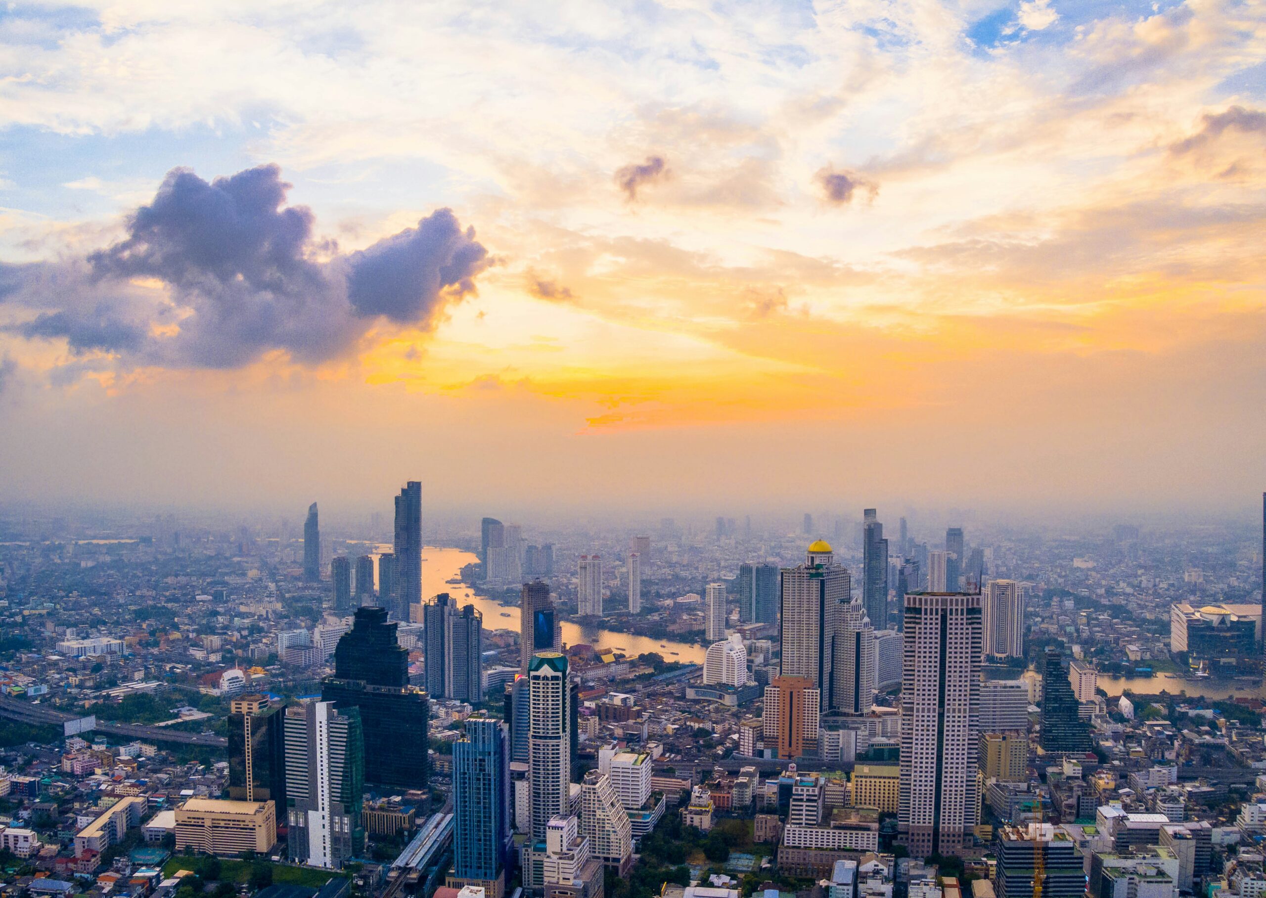 Bangkok cityscape under a bright yellow sunset and cloudy sky