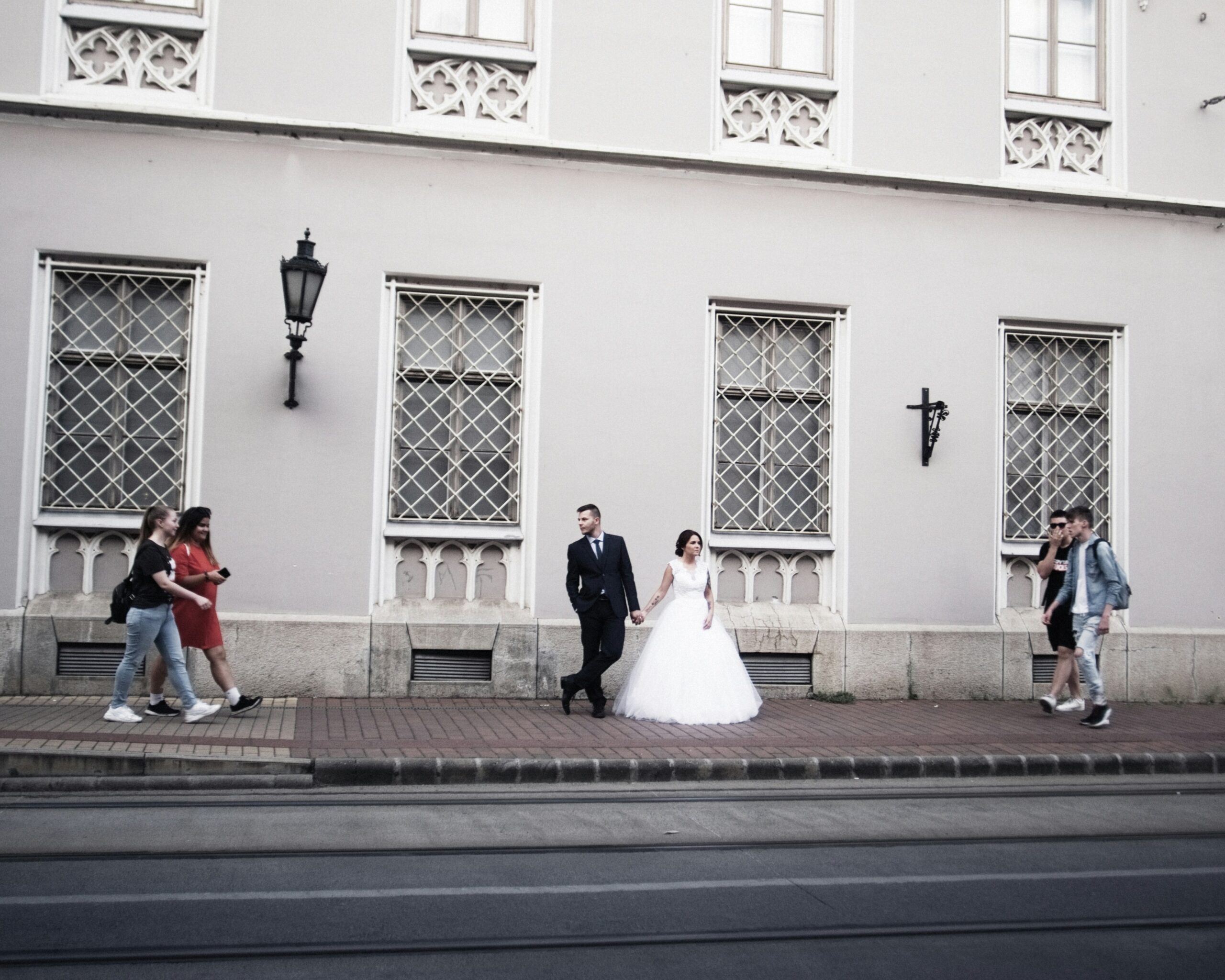 Bride and groom outside of a historical building in Budapest. People walking by.