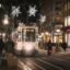 A tram driving down the street in Geneva at night, surrounded by Christmas lights.