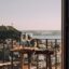 two wine glasses atop a table overlooking a balcony and Lisbon's neighborhoods, water, and hills