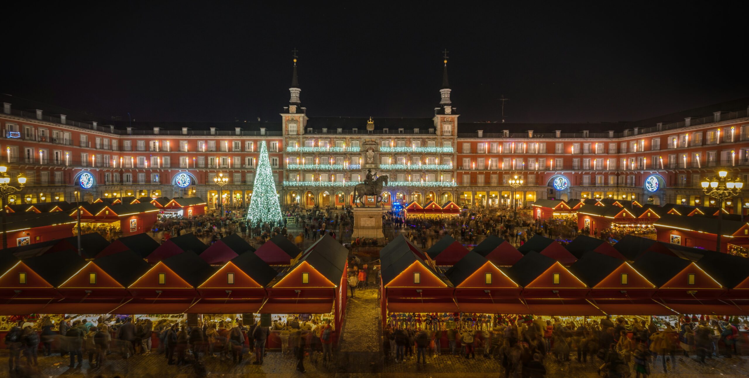 A Madrid Christmas market at night time. Many wooden stalls and christmas lights.