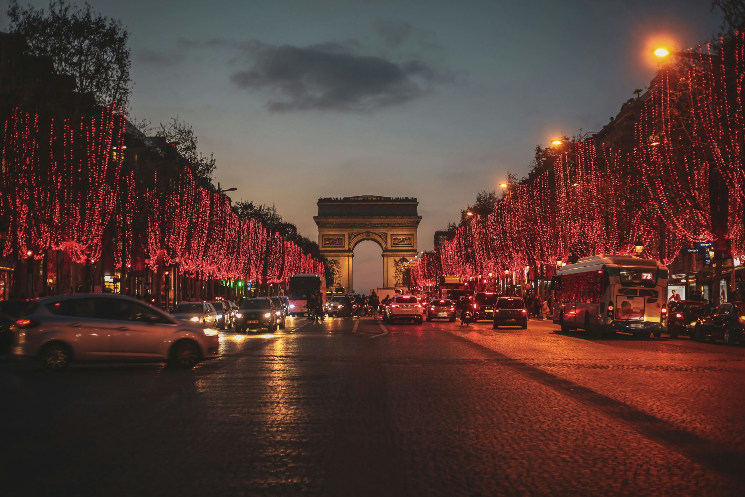 Champs Elysees with Christmas lights lining all the trees. Night time, so the red lights sparkle.