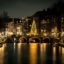 A Christmas tree lit up at night on a canal bridge