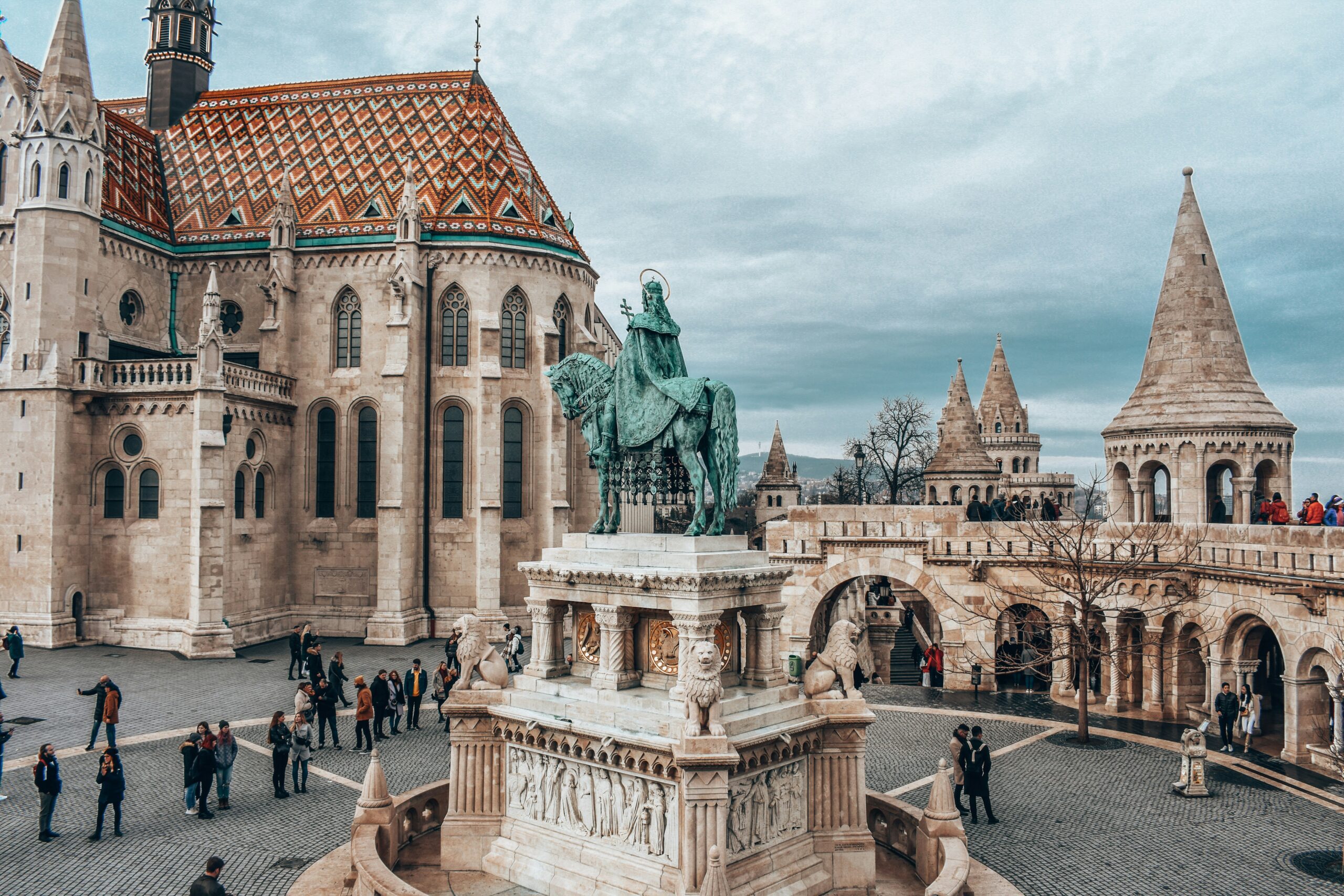 Old buildings in a square with a large statue of a man on a horse in the center.
