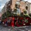The iconic red facade of The Temple Bar pub in Dublin, Ireland, decorated with flowers on a cobblestone street, a must-visit for travelers booking a Dublin airport taxi.