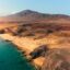 Aerial view of Lanzarote's volcanic coastline and golden sand beaches under a clear blue sky, ideal for travelers booking an airport taxi to Papagayo.