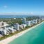 Aerial view of Miami Beach's coastline and luxury high-rise hotels along the turquoise Atlantic Ocean, a top destination for travelers booking a Miami airport taxi.