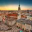 Aerial view of Munich city center featuring the historic Peterskirche and Old Town Hall at sunset, a primary location for travelers booking a Munich Airport taxi.