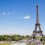 The Eiffel Tower and Champ de Mars in Paris, France, under a clear blue sky; a premier destination for travelers booking a Paris Airport taxi to their hotel.