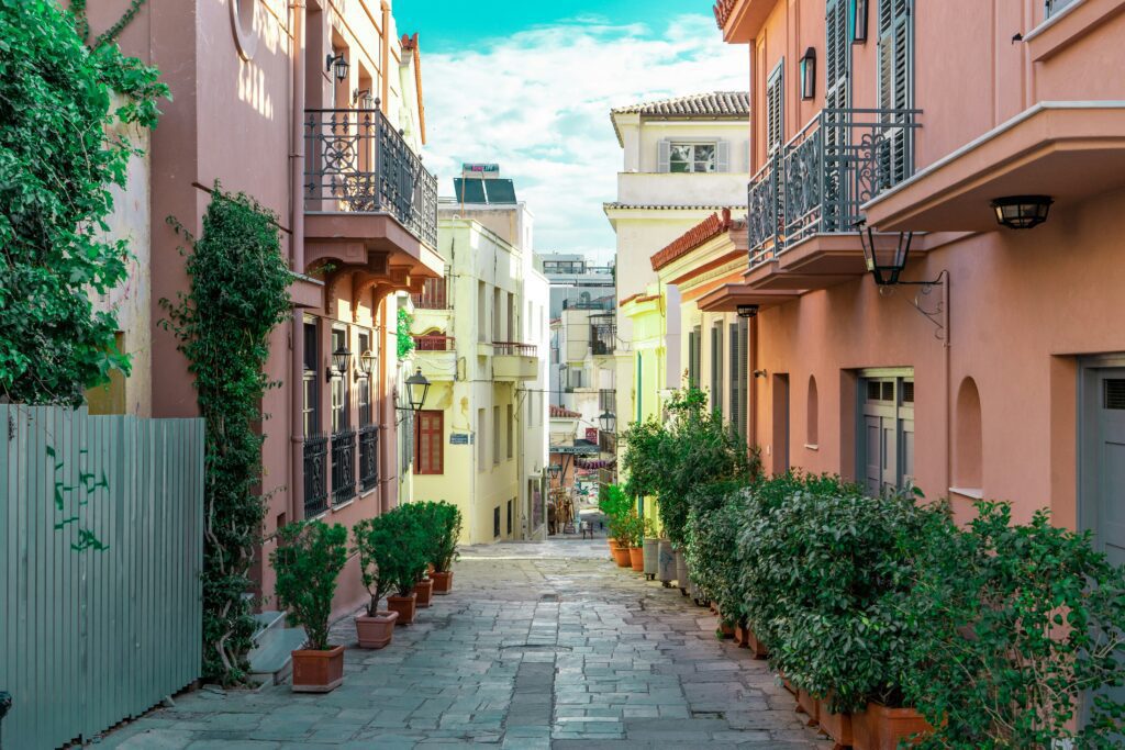 Cobblestone street in Plaka, Athens, lined with colorful buildings and potted plants