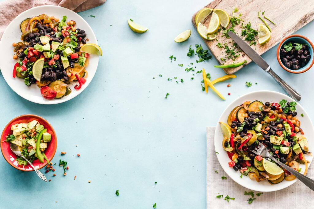 Overhead flatlay of Mexican-style veggie bowls with black beans, avocado, zucchini and lime