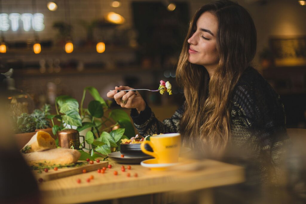 Woman enjoying a meal at a cozy restaurant table surrounded by potted plants