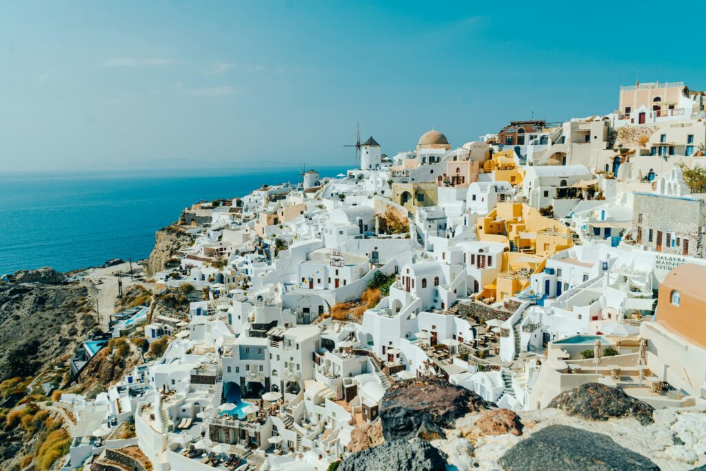 Panoramic view of Oia village with whitewashed houses and a windmill overlooking the Aegean Sea, Santorini