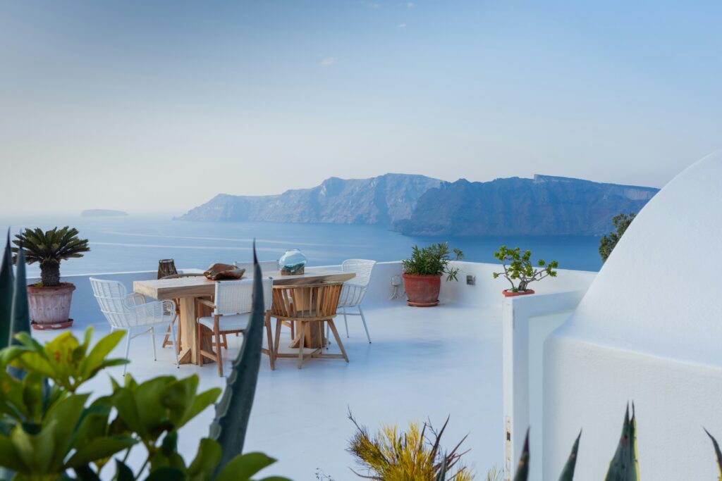 Whitewashed terrace with dining table overlooking the Santorini caldera and Aegean Sea