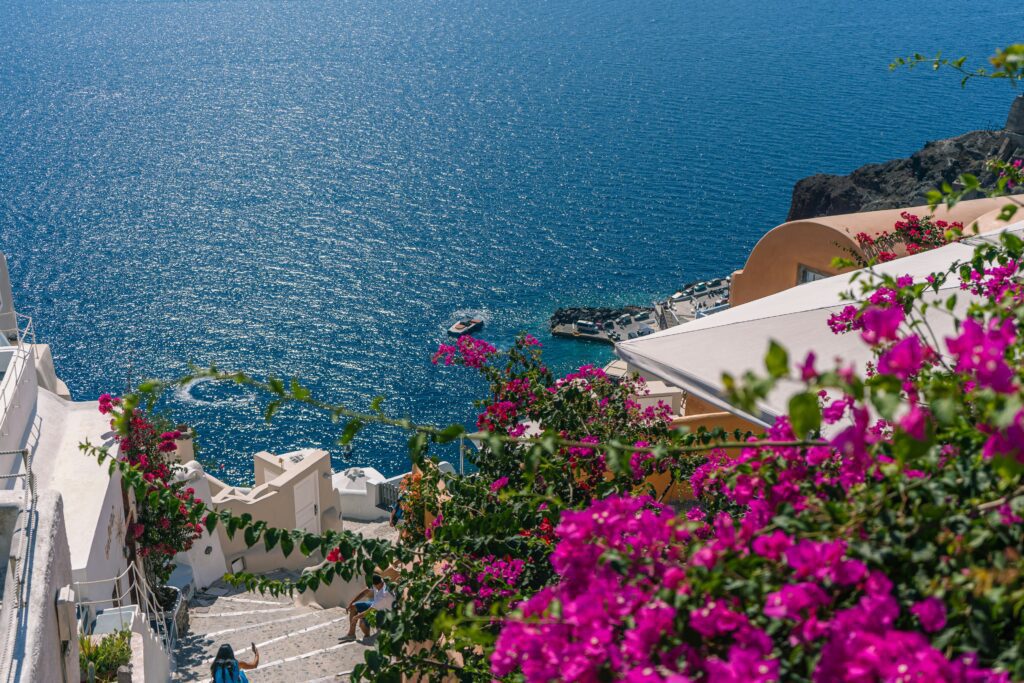 Whitewashed steps lined with pink bougainvillea leading down to Amoudi Bay, Santorini