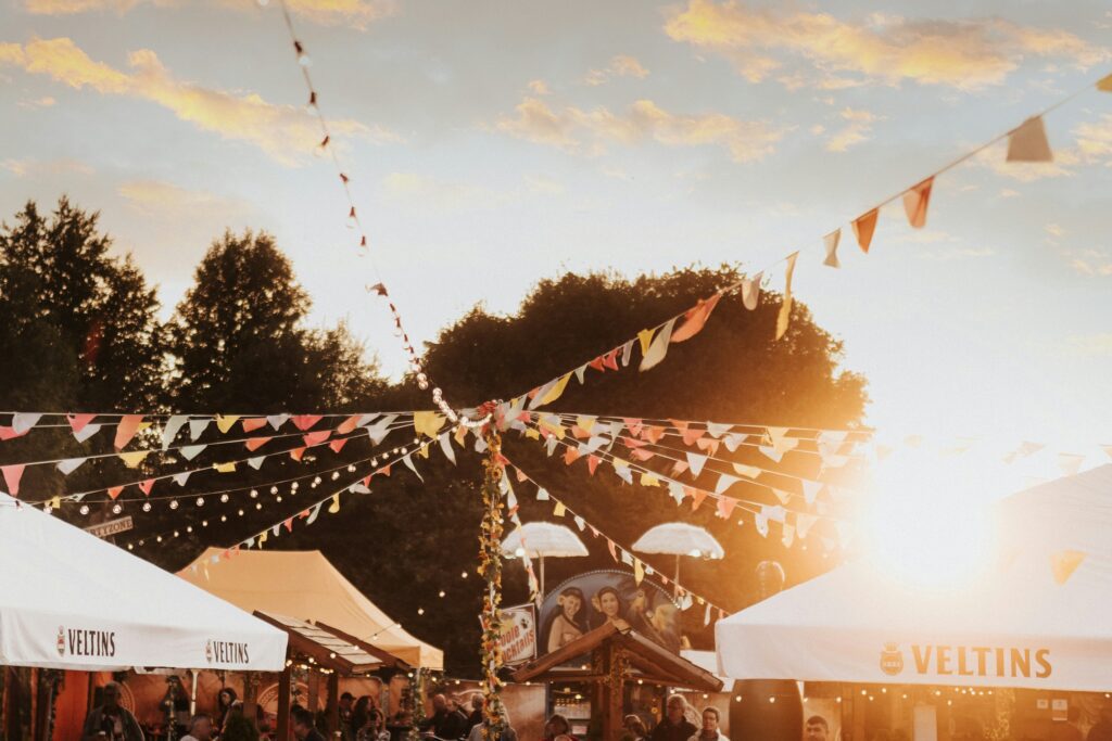 Festival food and drink area with colorful bunting and string lights at golden hour